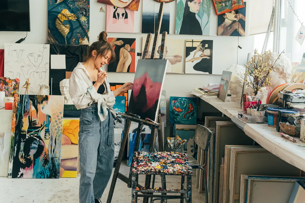 A young woman artist painting on canvas in her vibrant art studio filled with inspiring artworks.