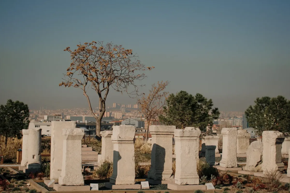 A serene cemetery with ancient gravestones and a view of the city skyline.