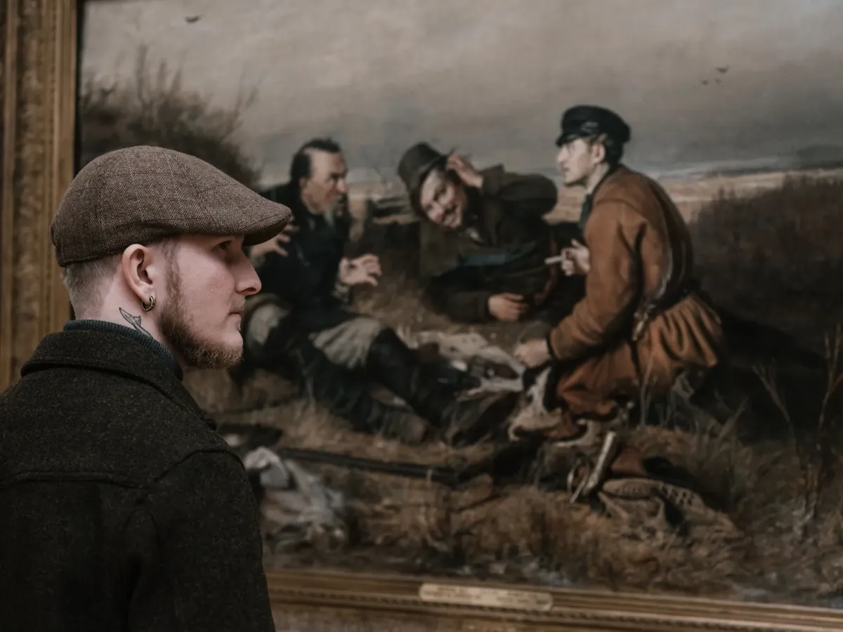 A man gazes at a historical painting in a museum with engaged attention.