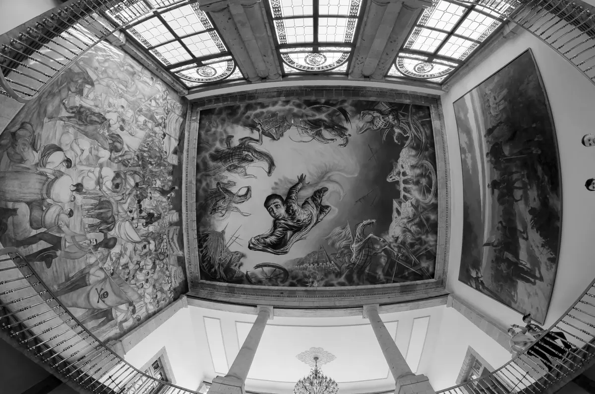 Black and white interior with historical murals on ceiling and walls.