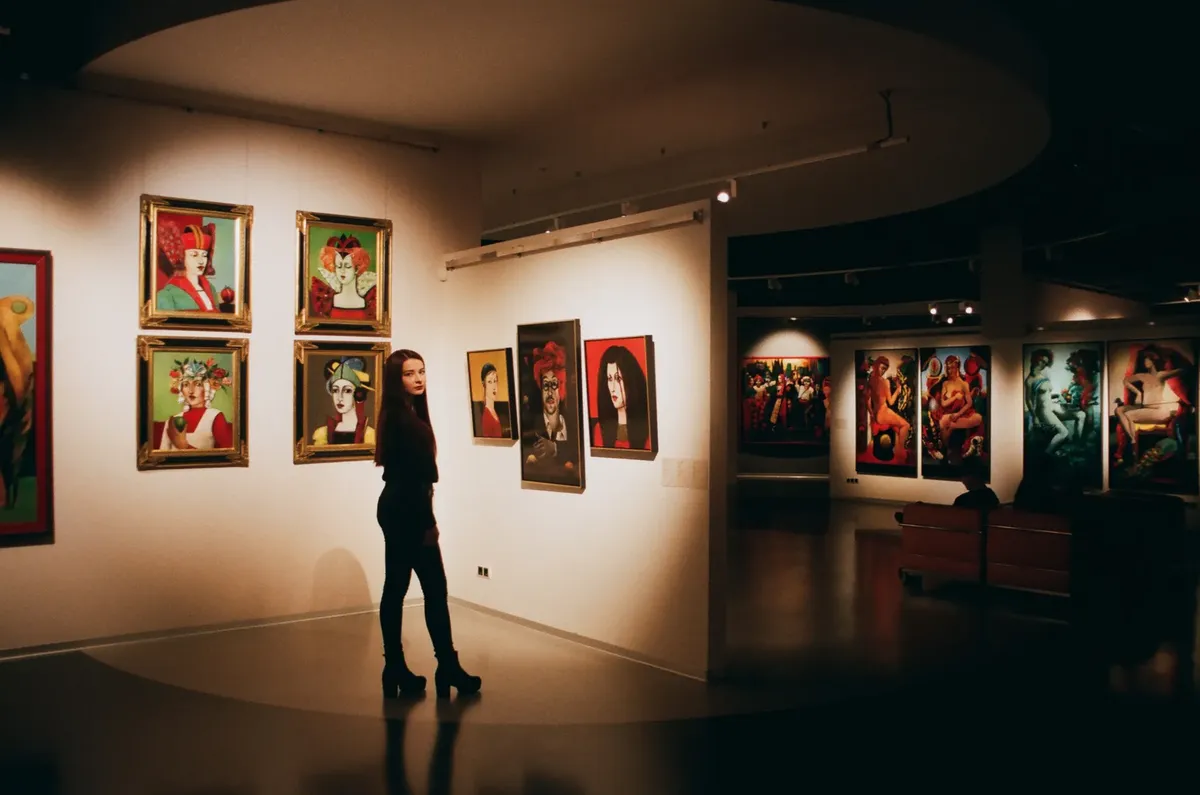 A woman admiring colorful paintings in a contemporary indoor art exhibition.