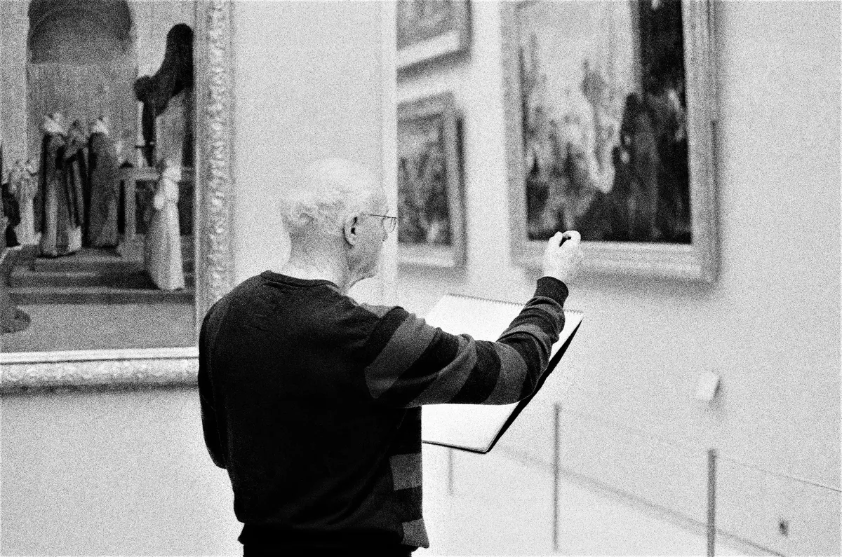 An elderly man sketching paintings in a museum, capturing art details.